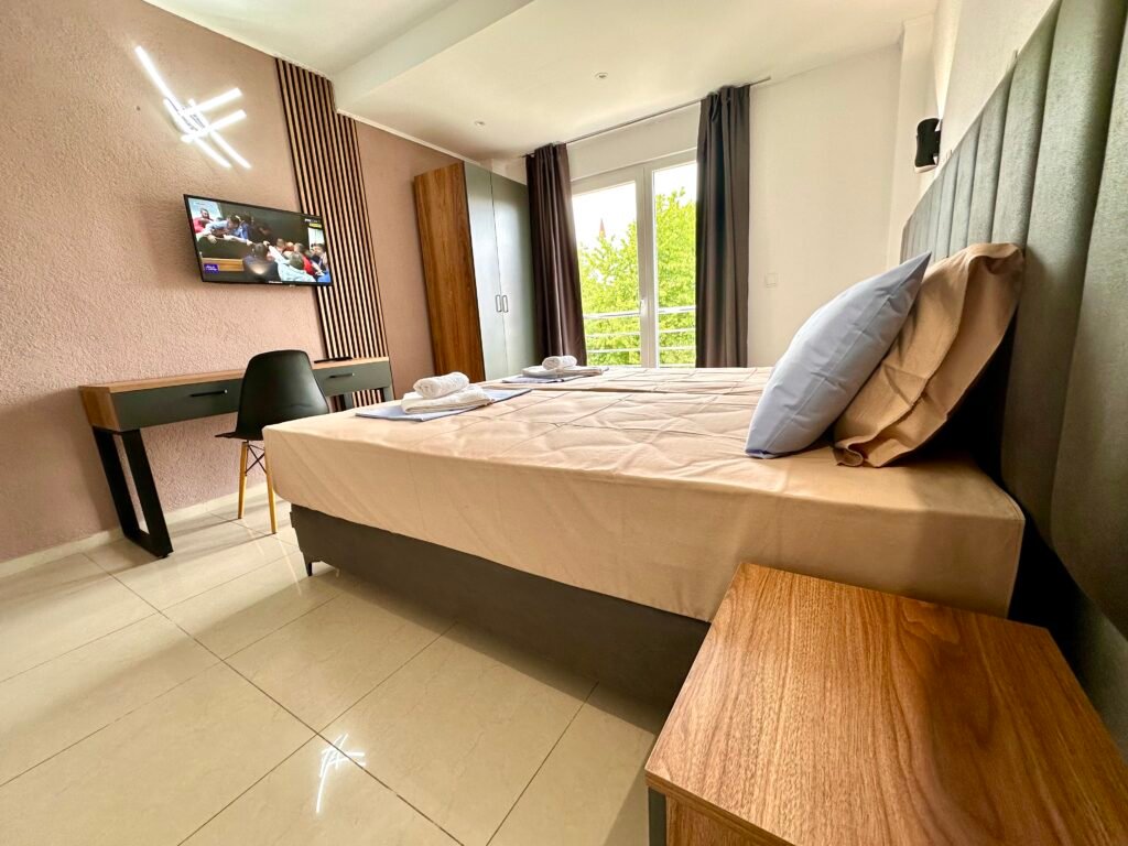 Double bed with folded towels beside the balcony doors