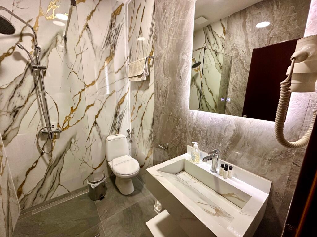 Marble-look bathroom with a washbasin, mirror and shower