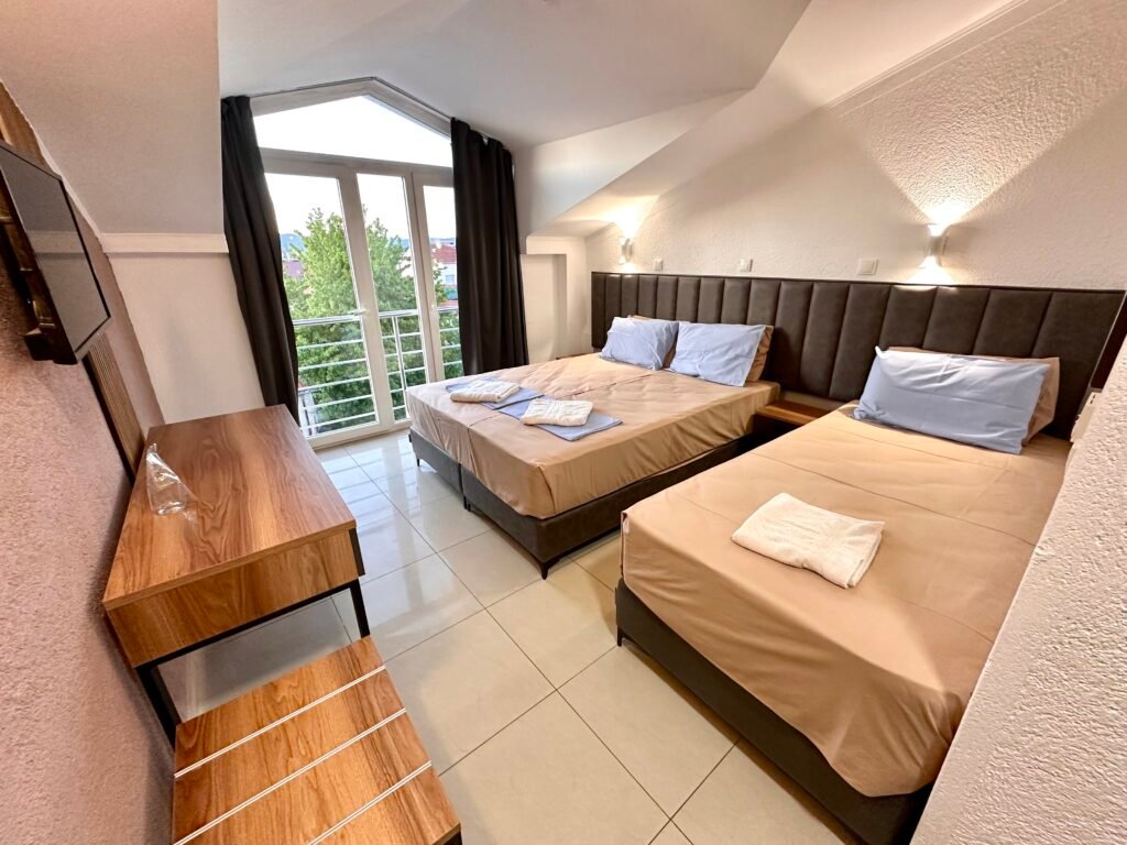 Guest room with two beds, a desk and balcony access