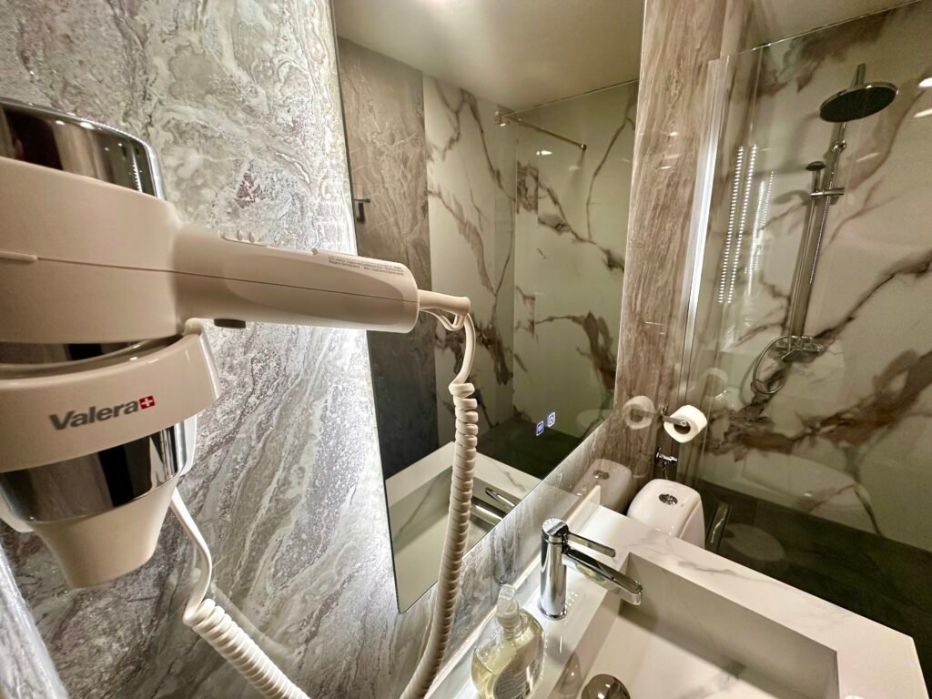 Bathroom with towels, a hairdryer and glass shower enclosure