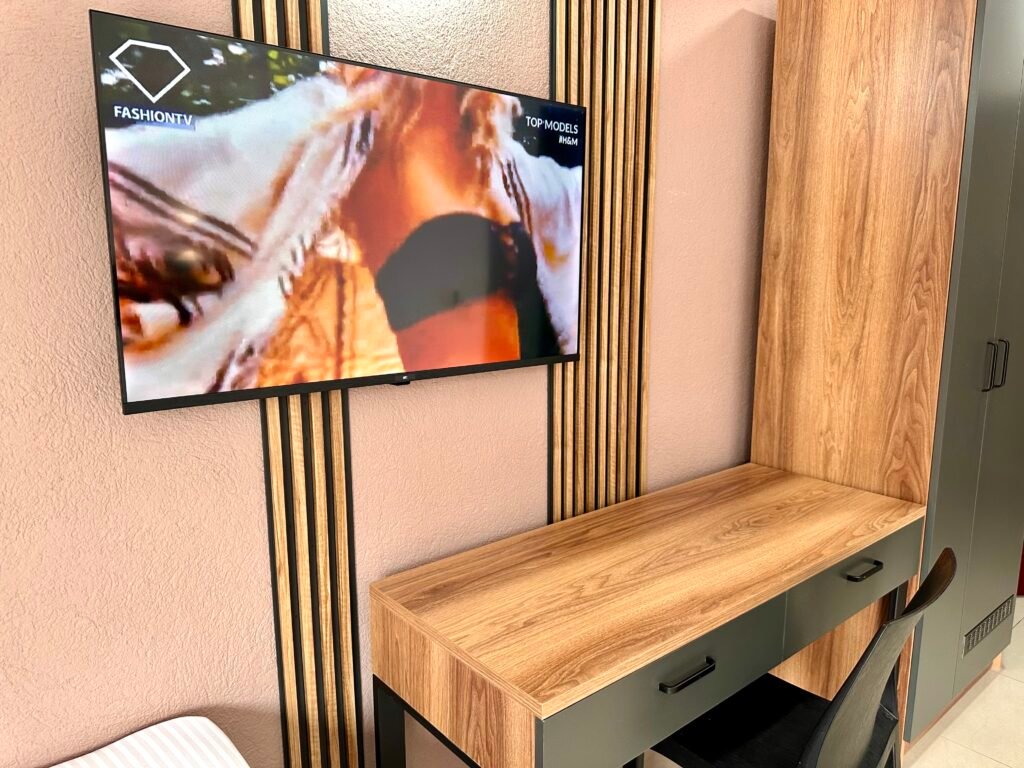 Wall-mounted television above a wooden desk in a guest room