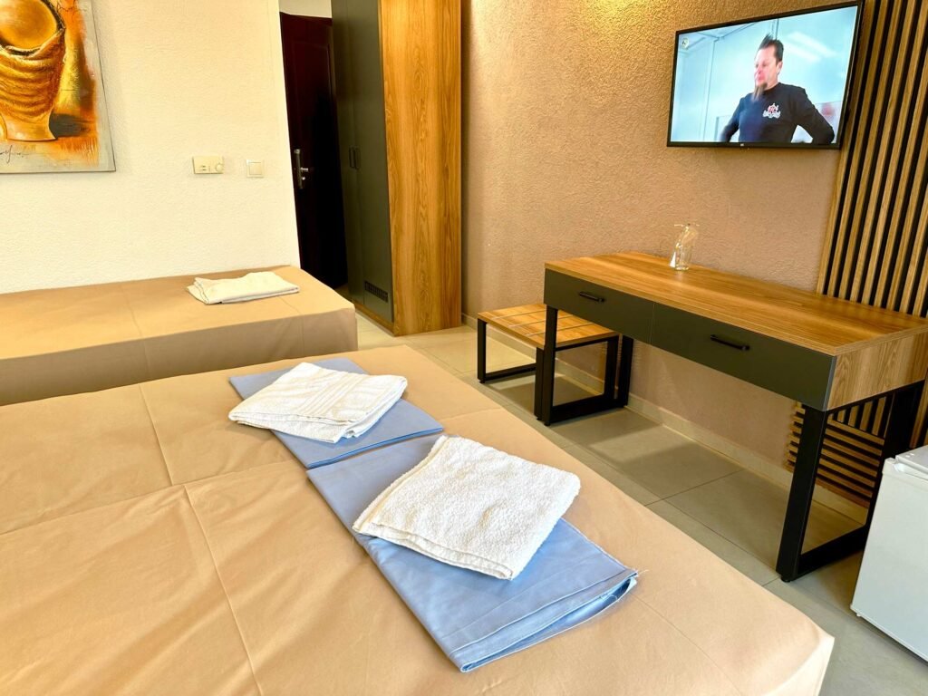 Standard room interior with a bed, desk and wall-mounted TV